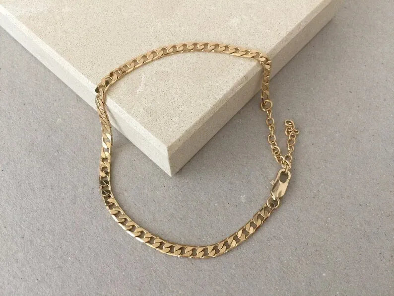 Gold chain Anklets on a light gray surface