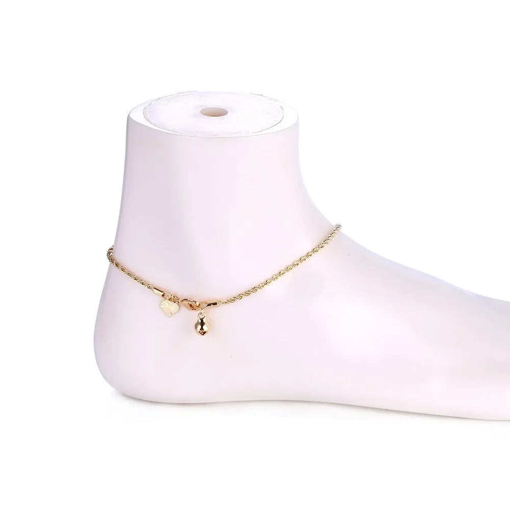 Gold anklet with small charms on a white mannequin foot against a white background