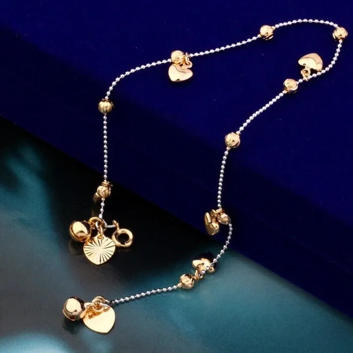 Gold anklet with heart-shaped pendants on a blue background
