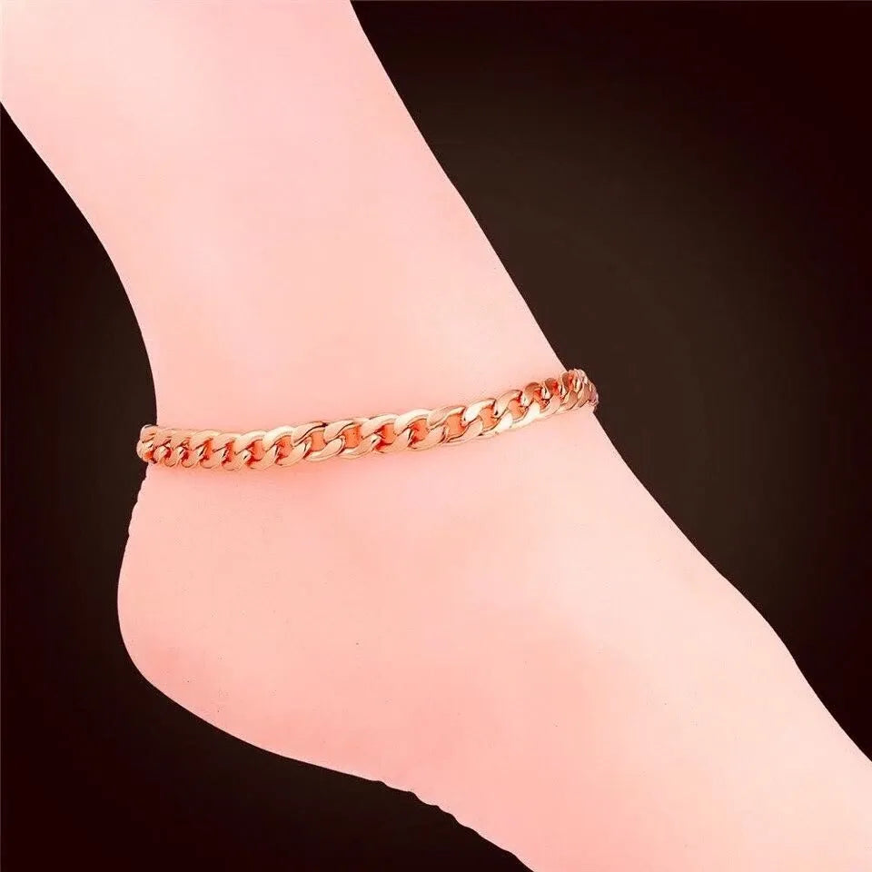 Rose gold chain anklet on a person's ankle against a dark background