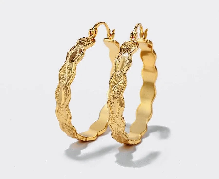 Gold hoop earrings with textured design on a light gray background