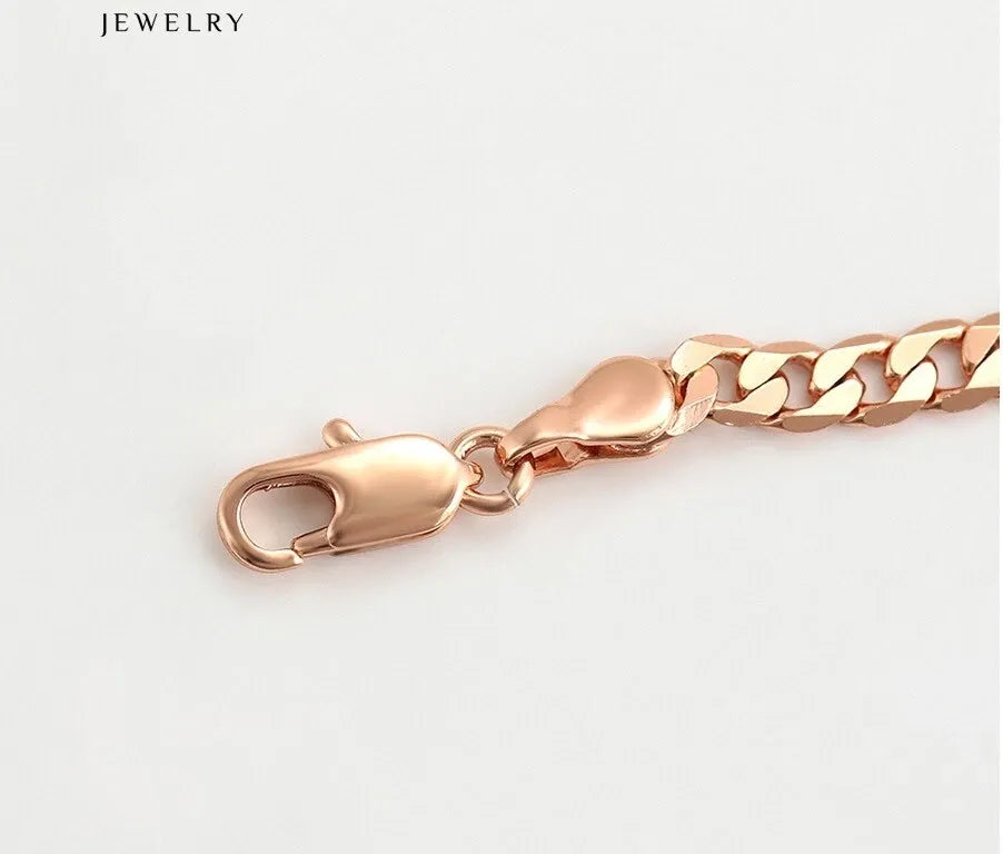 Rose gold chain anklet on a person's ankle against a dark background