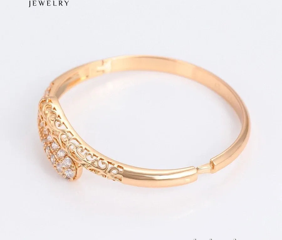 Gold bracelet with intricate design on a white background