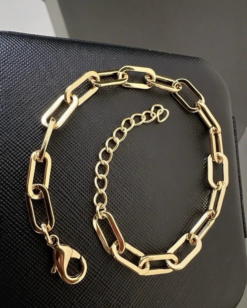 Gold chain bracelet on a black textured surface