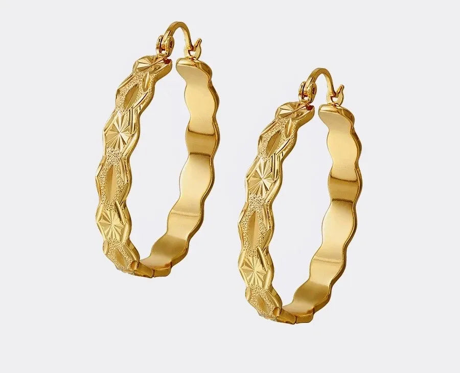 Pair of gold hoop earrings with textured design on a white background