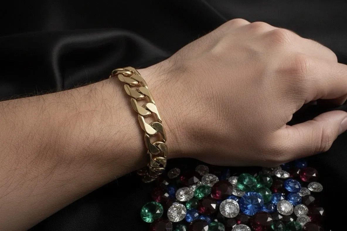 Gold bracelet on a wrist with scattered gemstones on a dark background
