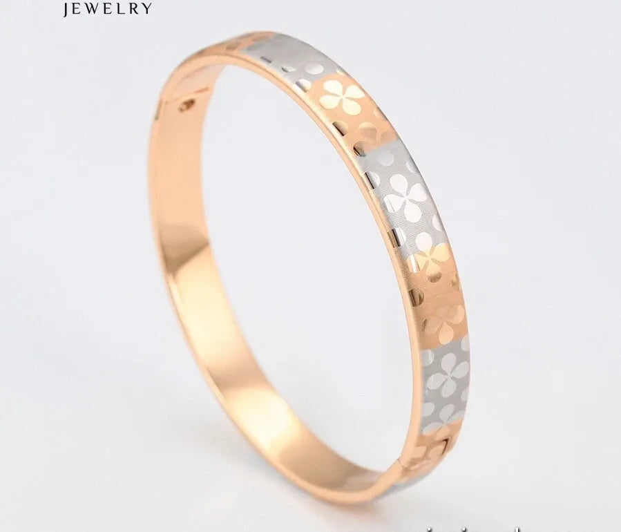 Two-tone gold and silver ring with floral pattern on a light gray background