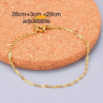 Gold Ankletson a cork surface with text indicating adjustable length.