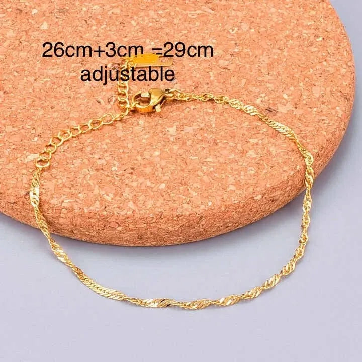 Gold Ankletson a cork surface with text indicating adjustable length.