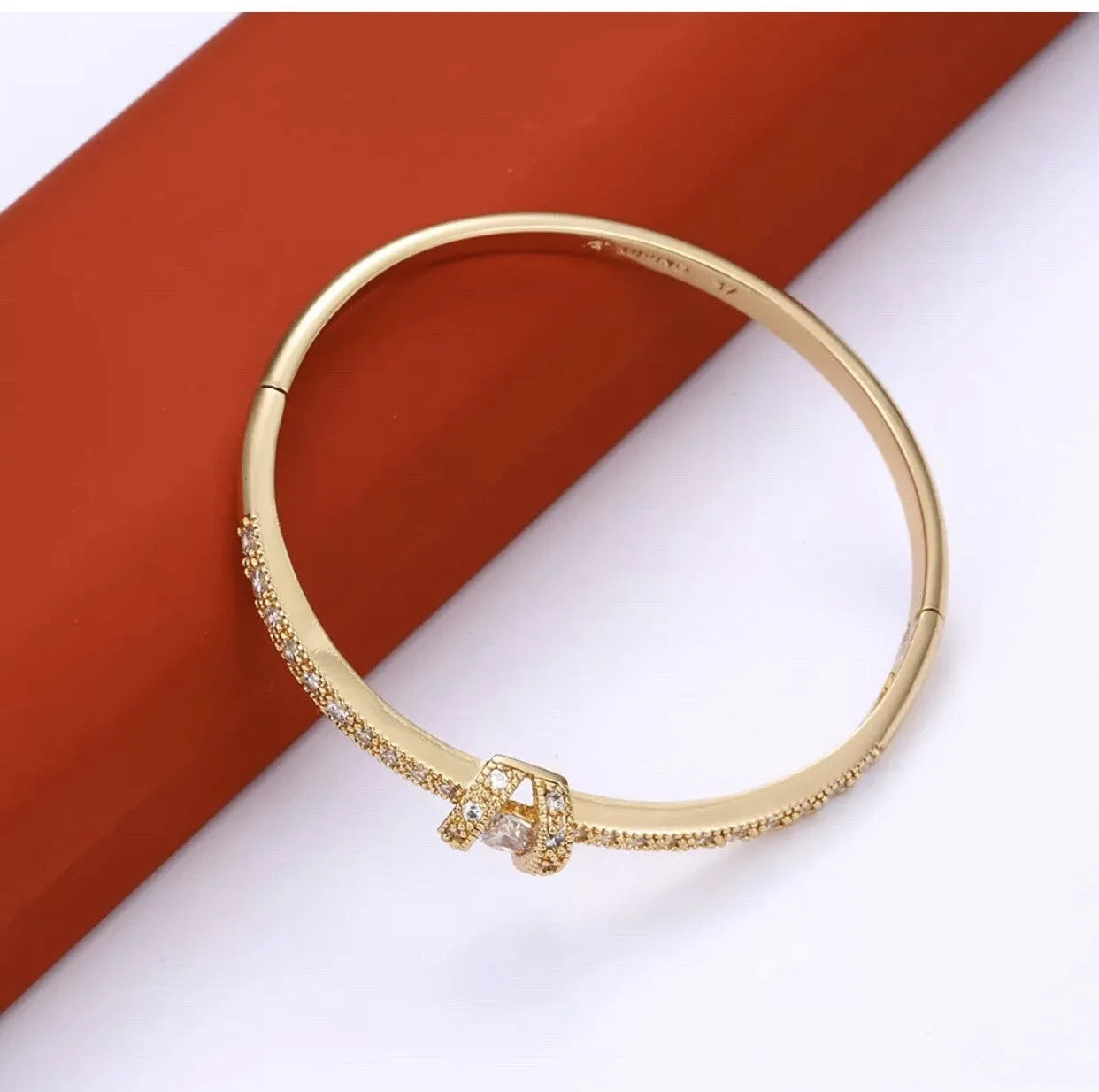 Gold bracelet with a clasp on a white and red background