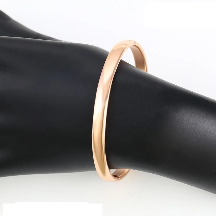 Rose gold bracelet on a black mannequin arm with a white background
