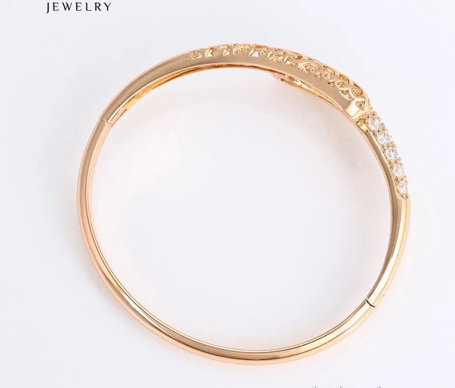 Gold bracelet with intricate design on a white background