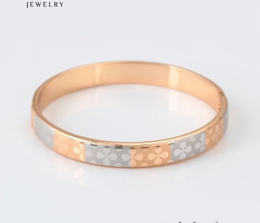 Two-tone gold and silver ring with floral pattern on a light gray background