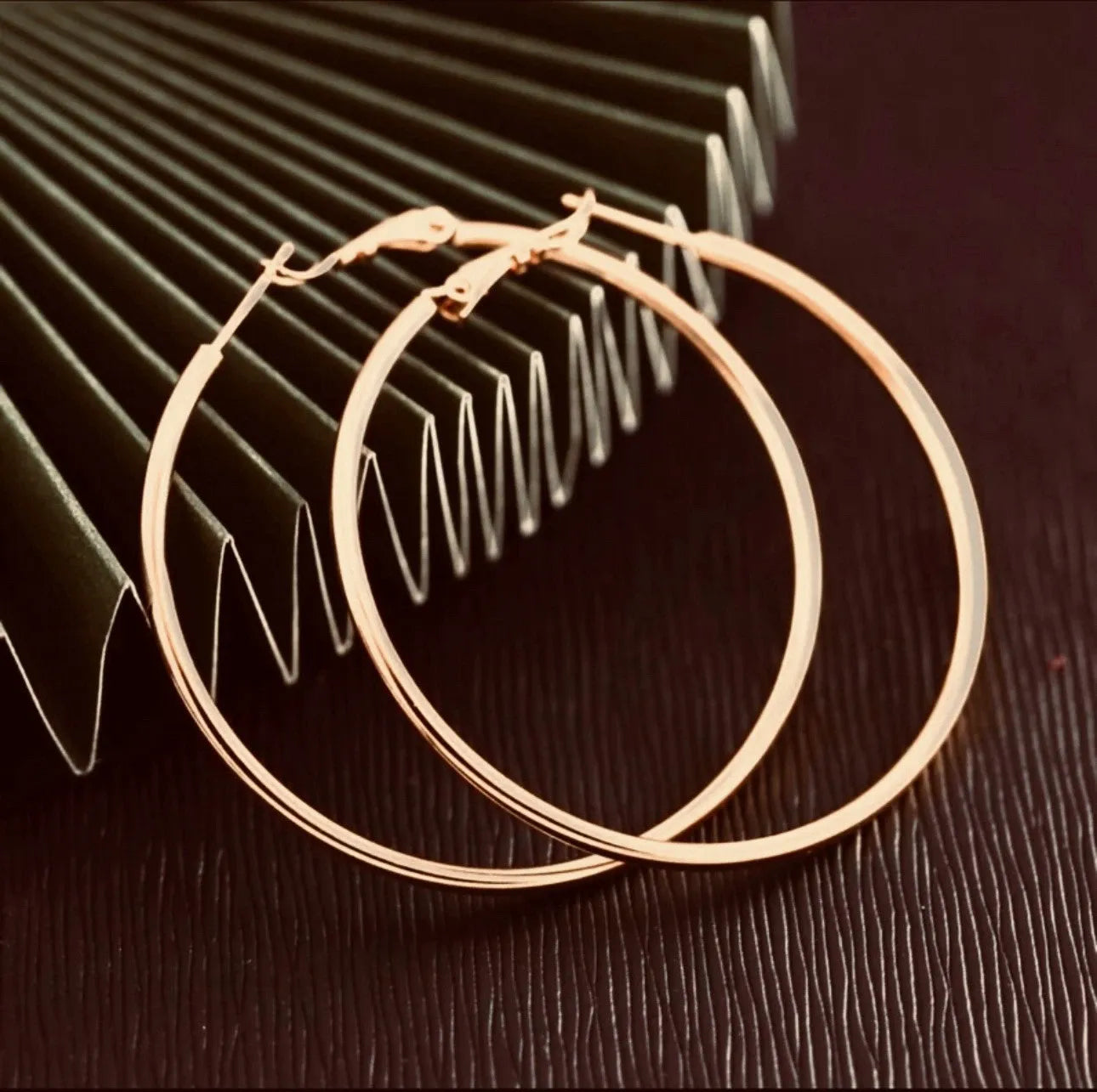 Gold hoop earrings on a textured surface