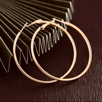 Gold hoop earrings on a textured surface