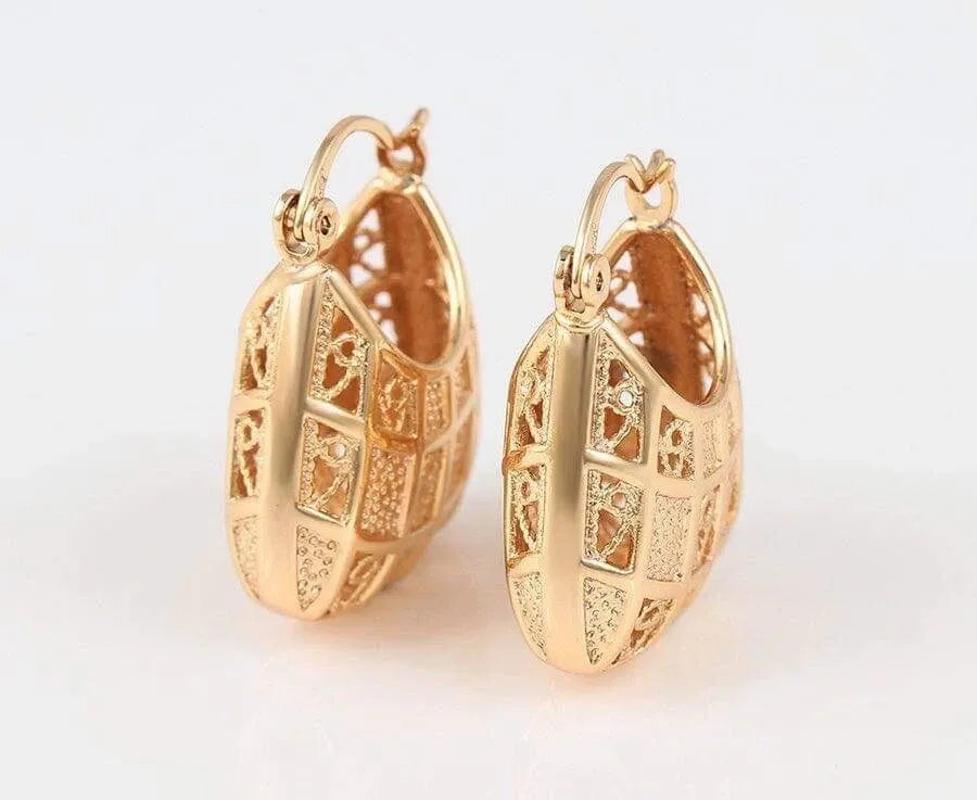 Gold hoop earrings with intricate designs on a light background