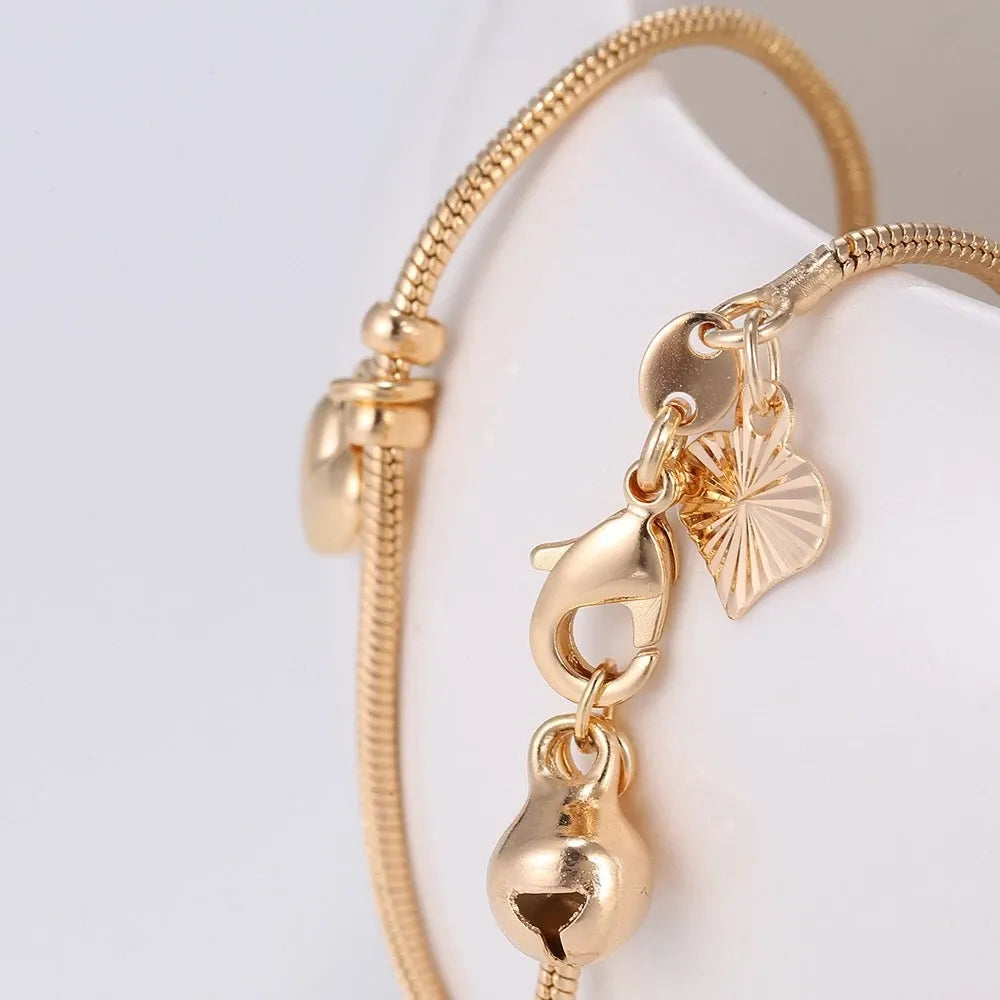 Gold bracelet with star and heart charms on a white background