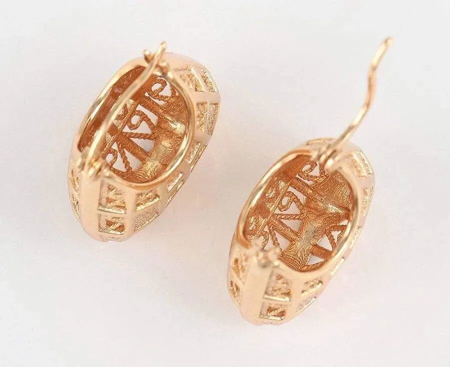 Pair of gold earrings with intricate designs on a white background