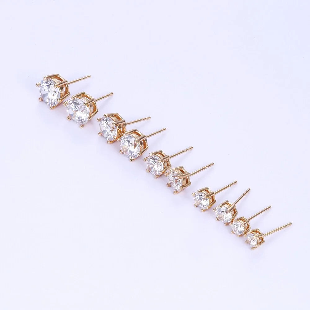 Set of gold earrings with clear gemstones on a white background
