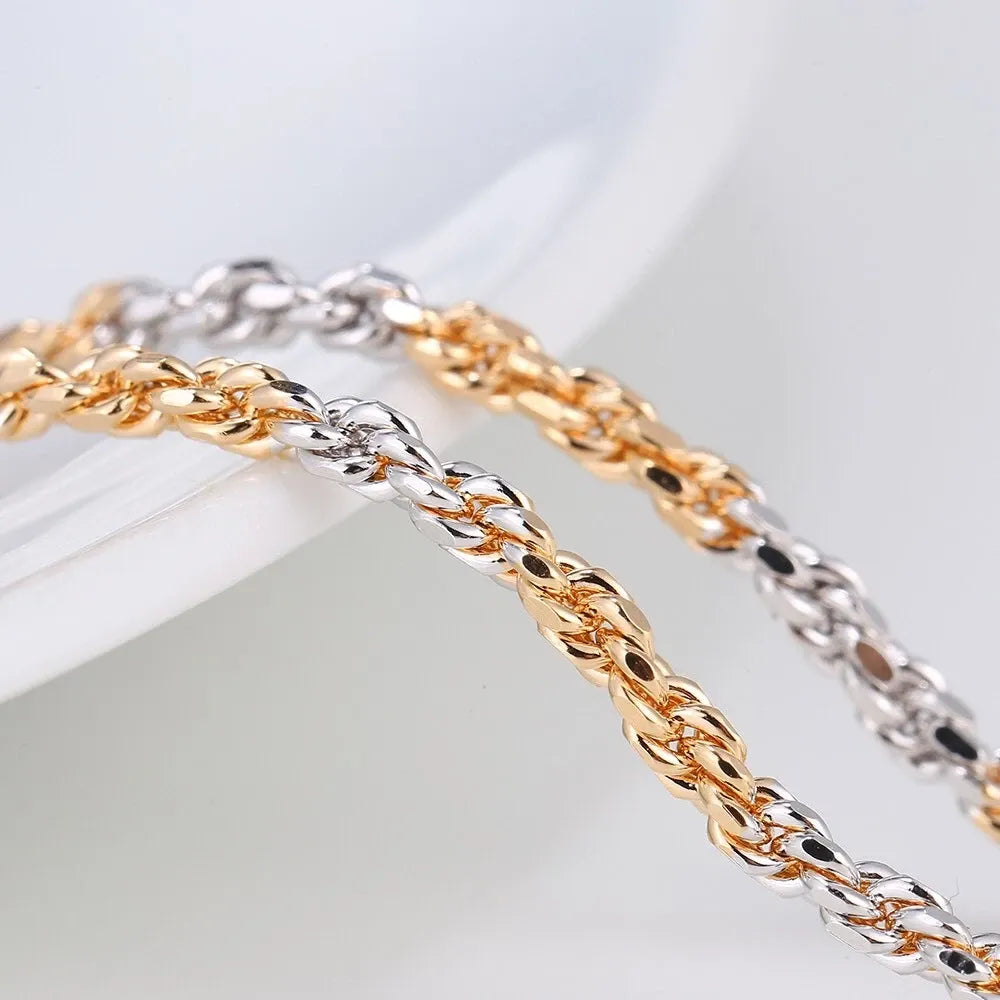 Two gold and silver chain anklet on a light gray background