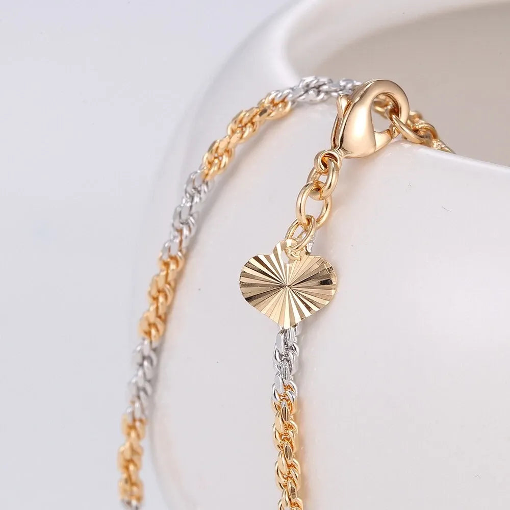 Gold and whiteanklet with a heart-shaped charm on a white background