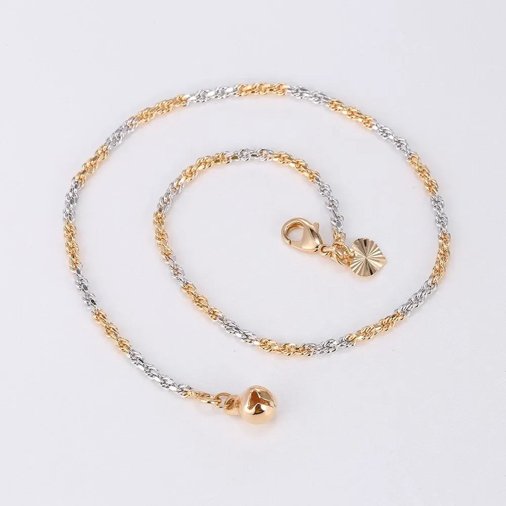 Gold and silver chain anklet with heart-shaped pendants on a light gray background