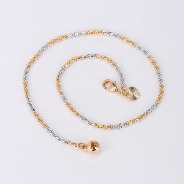 Gold and silver chain anklet with heart-shaped pendants on a light gray background