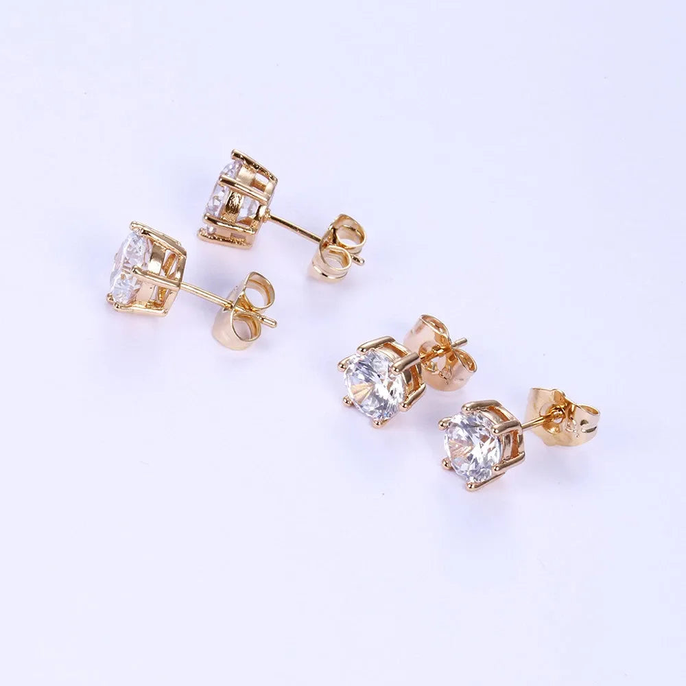 Gold stud earrings with clear gemstones on a light purple background