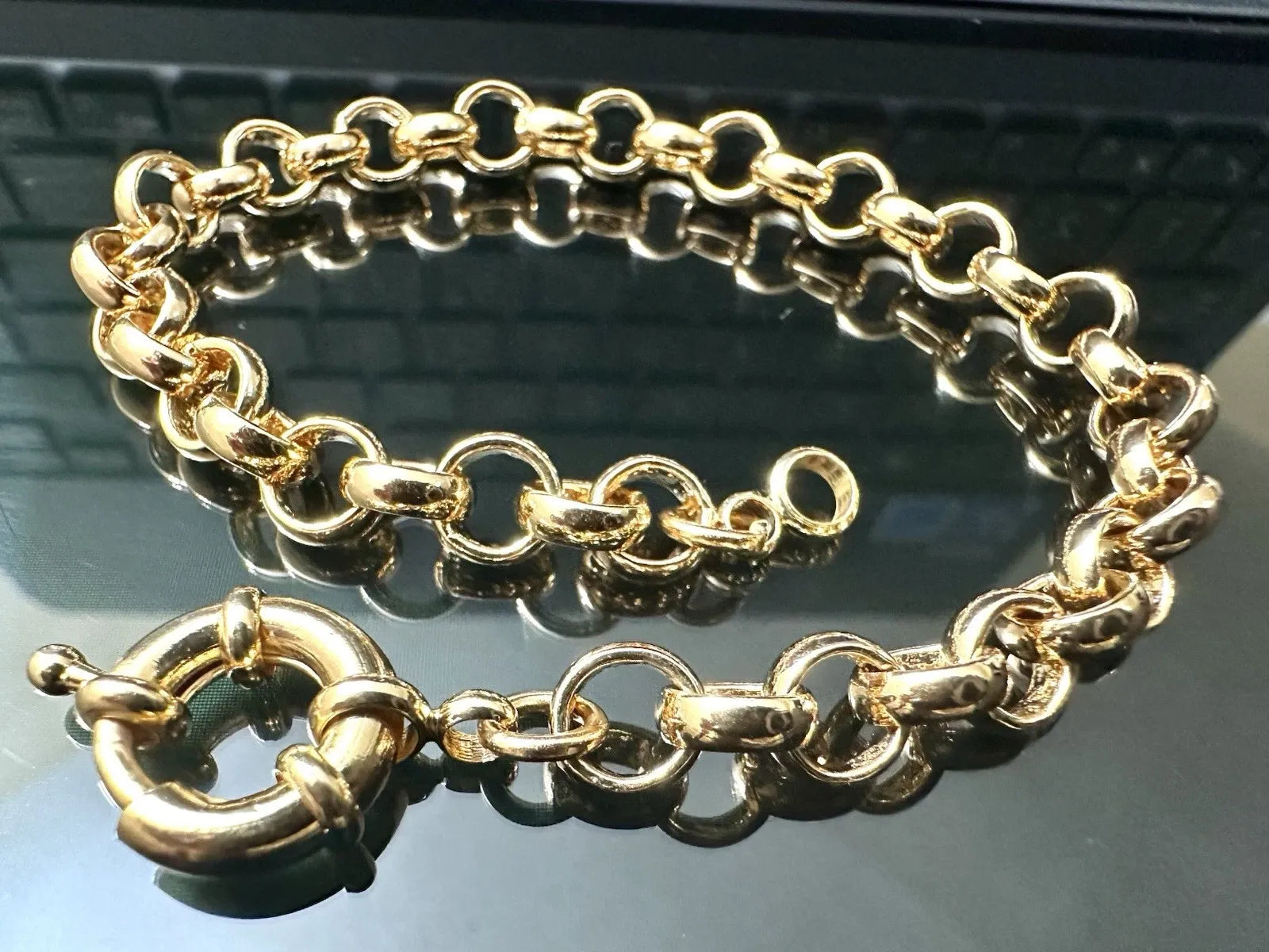 Gold chain bracelet on a reflective surface