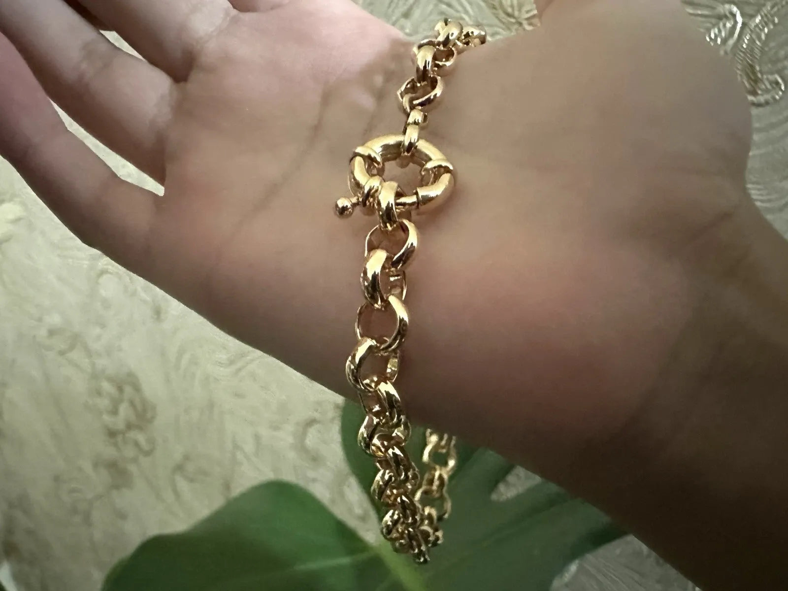 Gold chain bracelet on a person's wrist with a blurred background