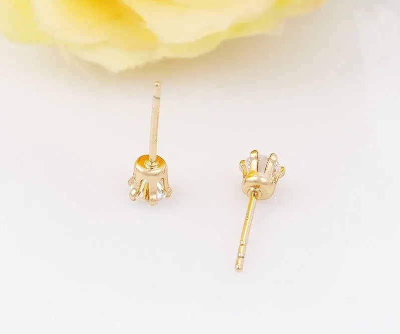 Gold stud earrings with clear gemstones on a white background