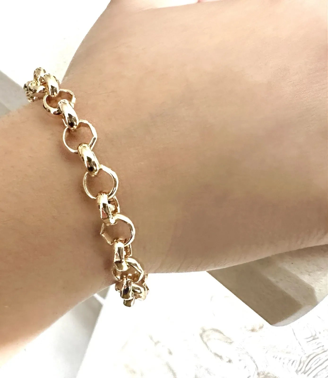 Gold chain bracelet on a wrist with a blurred background