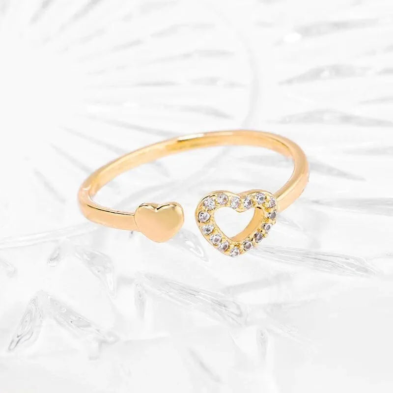 Gold heart-shaped ring with embedded stones on a white background