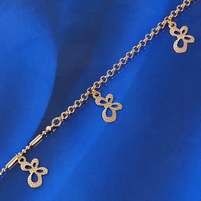 Gold anklet with butterfly charms on a blue fabric background