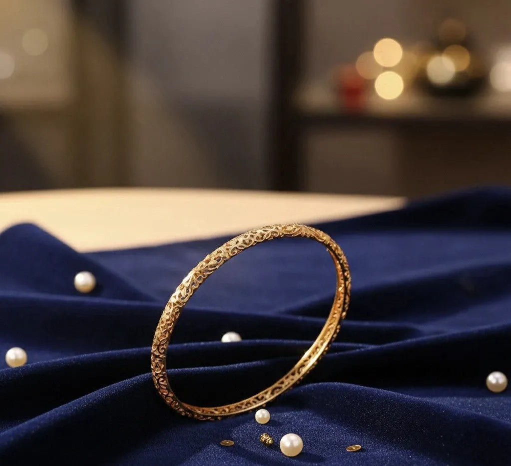 Gold bracelet on a blue fabric surface with pearls around