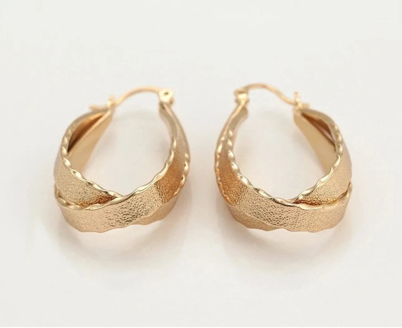 Gold hoop earrings on a light beige background