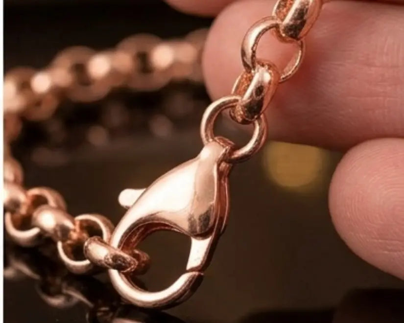 Rose gold chain with a clasp held by a hand against a blurred background