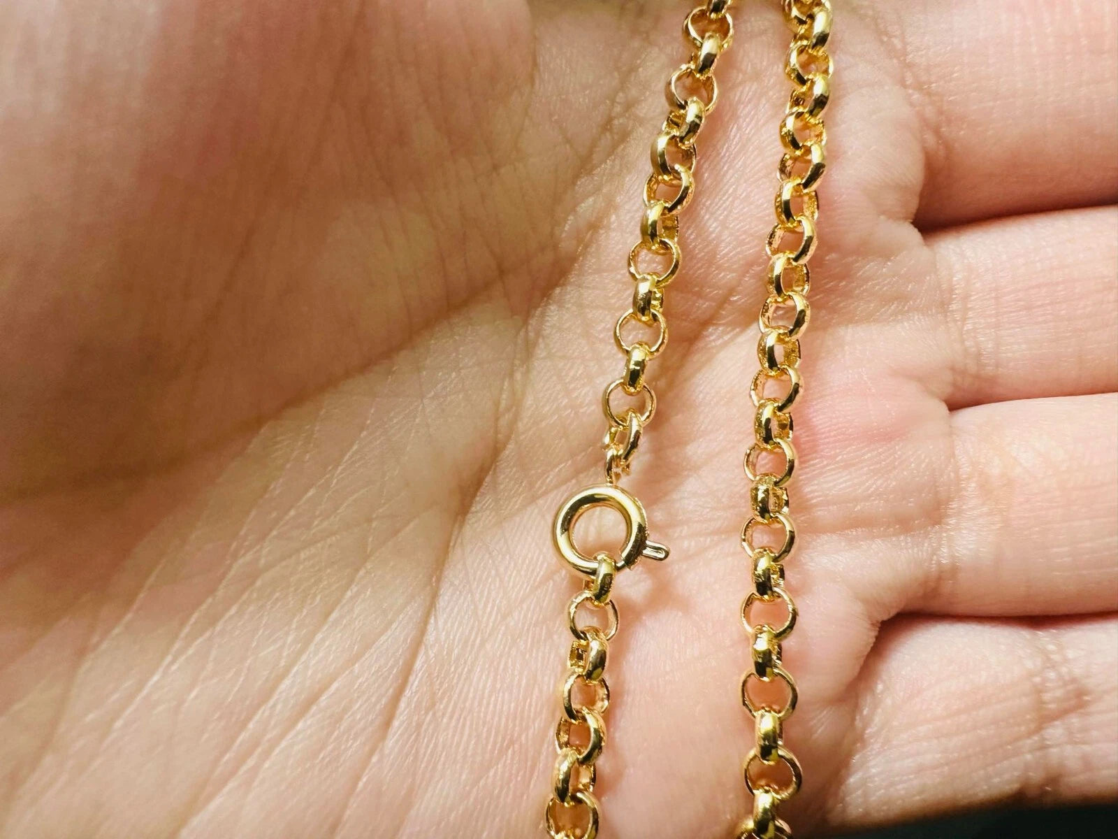 Gold chain with a ring clasp held between fingers