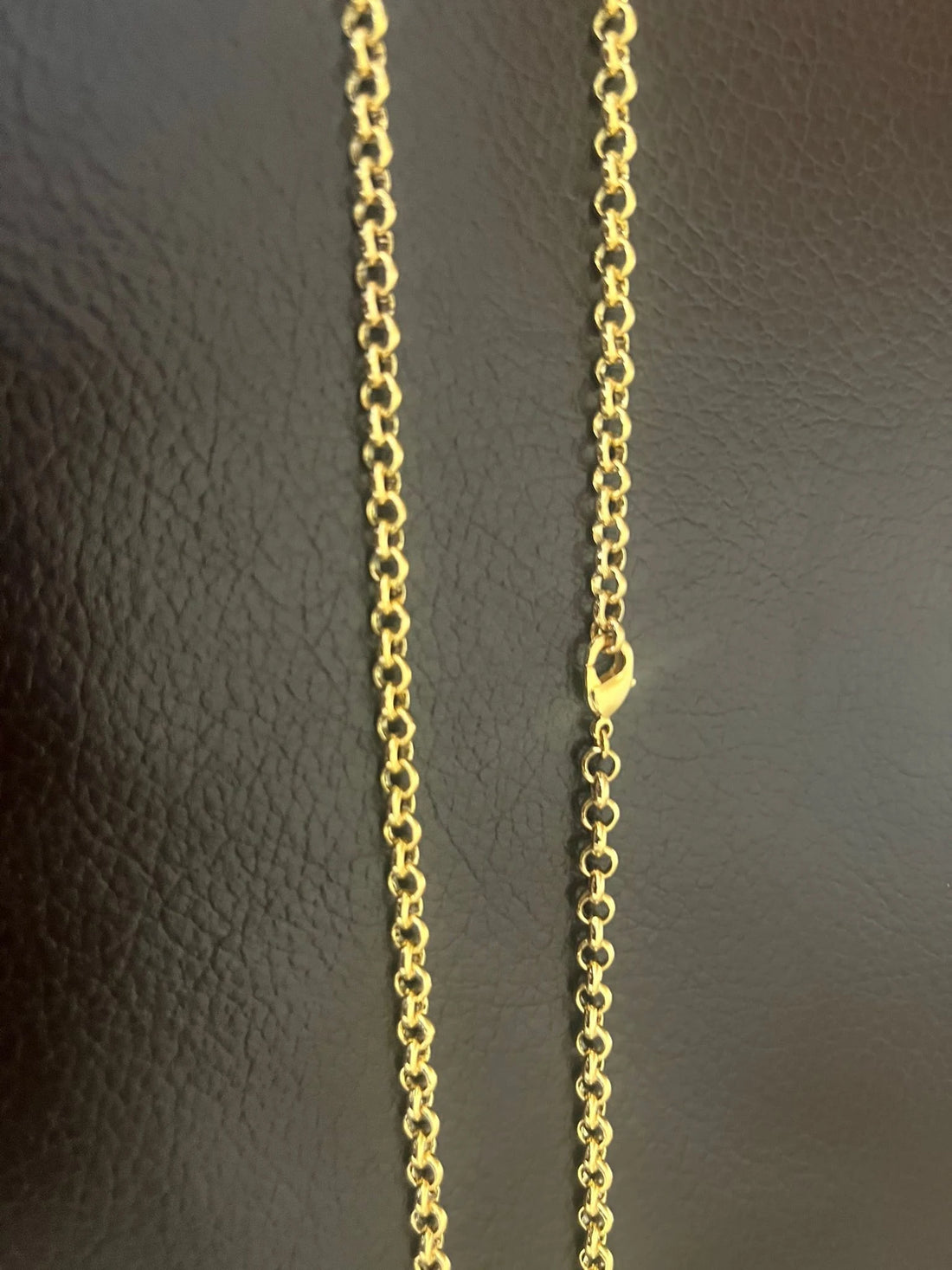 Gold chain necklace on a textured surface with a 'Premium Gold Plated' label.